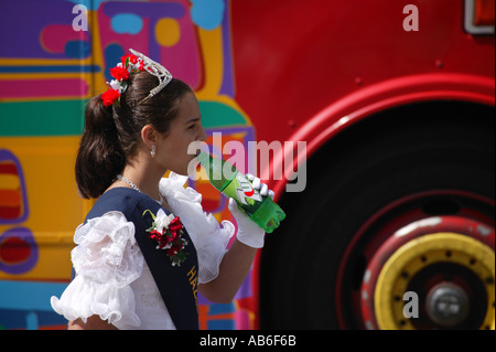 Carnival Queen drinking a soda walking alongside an old bus Stock Photo