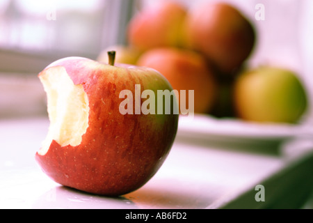 APPLES ON WINDOW SILL WITH ONE APPLE IN FOREGROUND WITH BITE TAKEN OUT OF IT. 1970 STYLE COLOR BALANCE Stock Photo