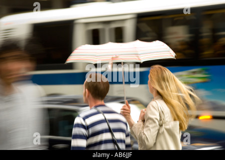 Couple Walk in the Rain Under Umbrella in City Stock Photo