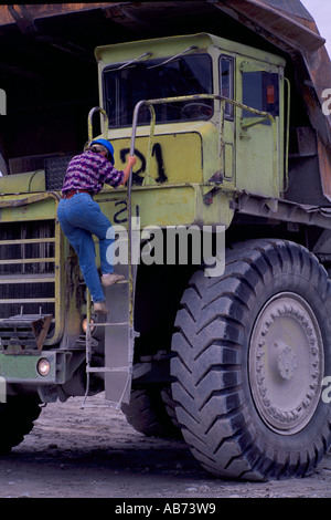 Texada Island, BC, British Columbia, Canada - Woman climbing up / down ladder on Big Mining Dump Truck at Limestone Quarry Mine Stock Photo