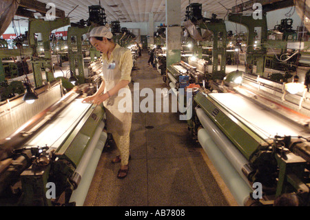 A female worker inspects machines in a traditional silk thread factory in Hotan Xinjiang China Stock Photo