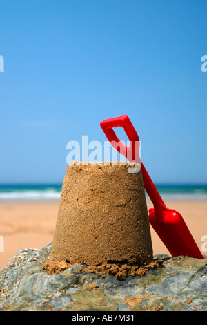 Sandcastle and red spade on rock. Stock Photo