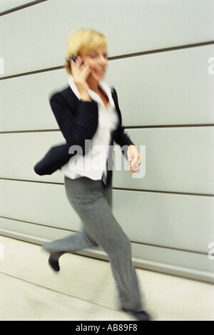 Running woman using a cellular telephone Stock Photo