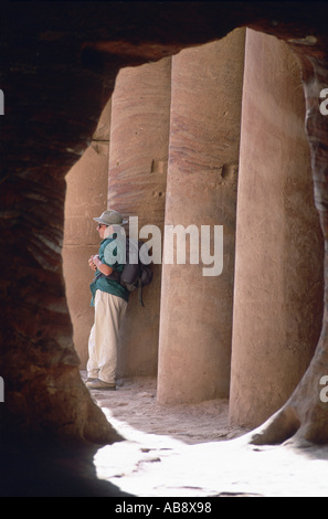 rucksack tourist in rock city Ptra, at the tomb of Onashu, seen out of rock passage, leaning at temple pillars, Jordan, Ptra. Stock Photo