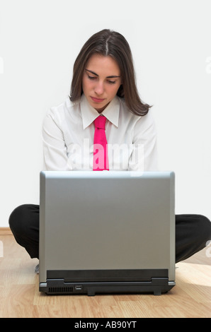Serious young business woman sitting on floor using laptop Stock Photo