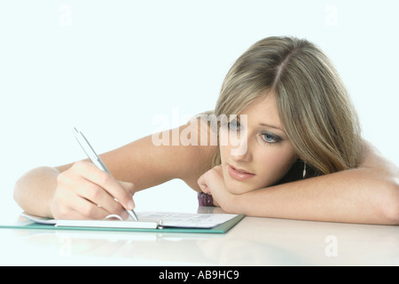 bored blond woman writing in note book. Stock Photo