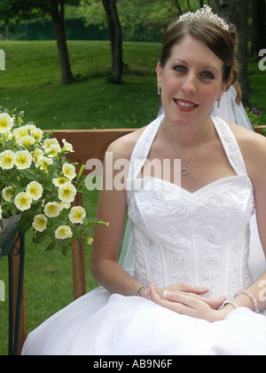 Bride Sitting by Flowers in [Wedding Dress] Stock Photo