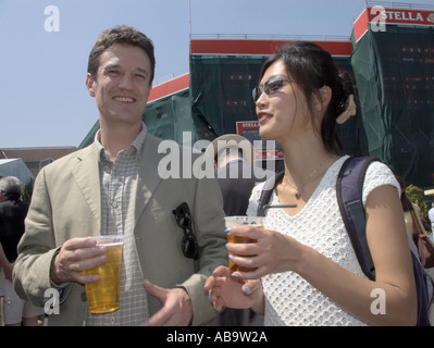 man and woman standing outside chatting and enjoying a drink Stock Photo