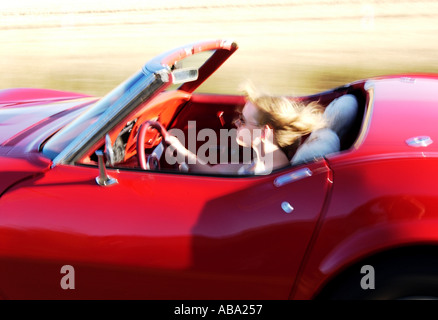 blond girl driving red convertible corvette Stock Photo