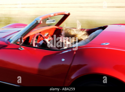 blond girl driving red convertible corvette Stock Photo