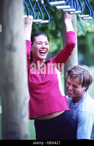 Man helping woman on monkey bars Stock Photo