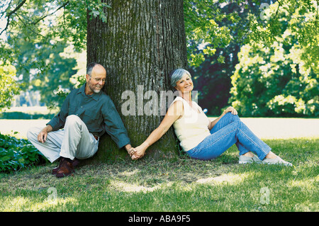 Couple sitting under tree Stock Photo