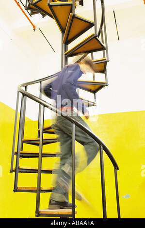 Man descending spiral stairs Stock Photo