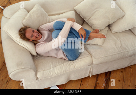 Girl curling up on sofa Stock Photo