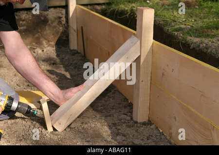Screwing in a screw in a piece of wood which holds the plank form in which concrete will be cast Stock Photo