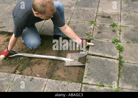 Man using a spade to lift paving stones Stock Photo