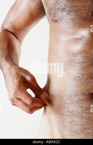 close up of mans hands pinching fat on waist Stock Photo