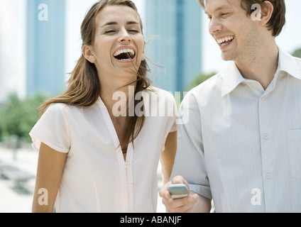 Young couple laughing as man holds cell phone Stock Photo