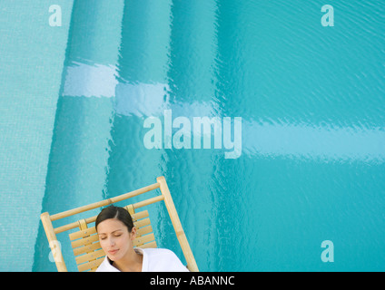 Woman sleeping in lounge chair next to pool Stock Photo
