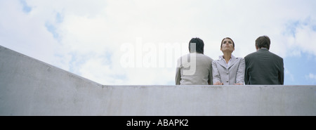 Woman standing between two men with backs turned Stock Photo