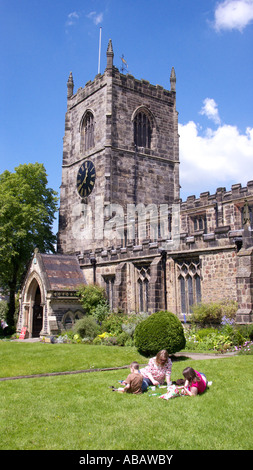 People relaxing on the grass in front the Holy Trinity Church Skipton North Yorkshire Stock Photo
