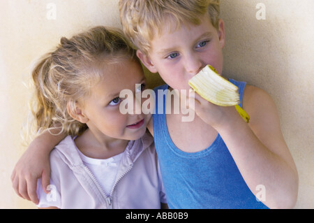 Boy hugging sister and eating banana Stock Photo