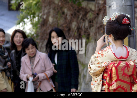 Kyoto, Japan, Geisha Taking a Photo for Tourists During Cherry Blossom Festival Stock Photo