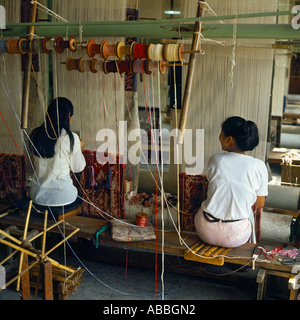 Silk Carpet Factory with two women working skillfully at looms with their backs to the camera in Shanghai China Stock Photo