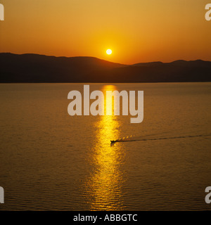 Golden sunset over Argostoli Bay with ripples and wake of boat in reflections on Cephalonia Island The Greek Islands Stock Photo