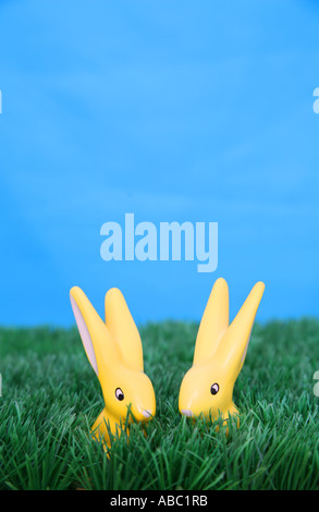 Two yellow easter bunnies with long ears are sitting on a green meadow in front of a blue sky Stock Photo