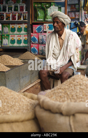 A man sits at a stall selling foodstuffs within the Devraja Urs Market in Mysore, Karnataka, India. Stock Photo