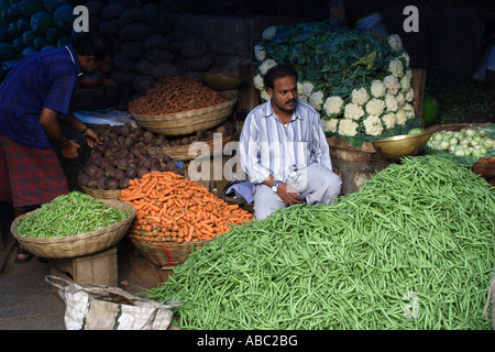 A man sits at a stall selling vegetables within the Devraja Urs Market in Mysore, Karnataka, India. Stock Photo