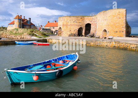 Rowing boat in Northumberland harbour overlooked by lime kilns Stock Photo