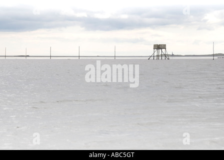 Refuge box on Pilgrims Causeway Lindisfarne with tide in Stock Photo