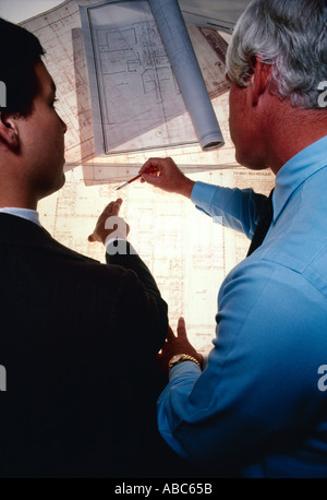 Architecture / Business - Architects, businessmen, executives inspecting, reviewing, examining blueprints on a light table. Stock Photo