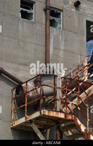 Rusty old emergency external staircase on outside of old derelict industrial factory building Stock Photo
