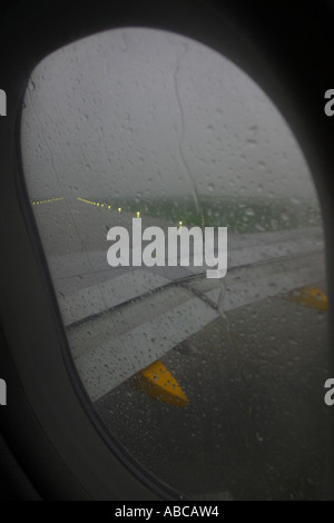 Flying in bad weather taking off in heavy rain storm view from passenger window Stock Photo