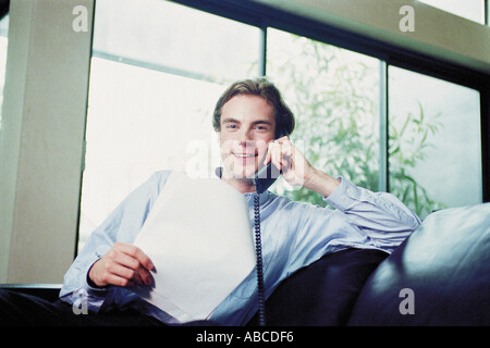 Man sitting on sofa with telephone Stock Photo