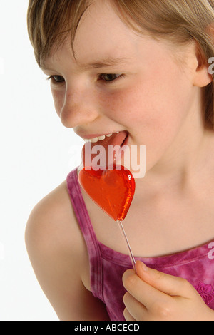 Girl licking heart shaped lollipop