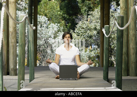 Woman with computer doing yoga Stock Photo