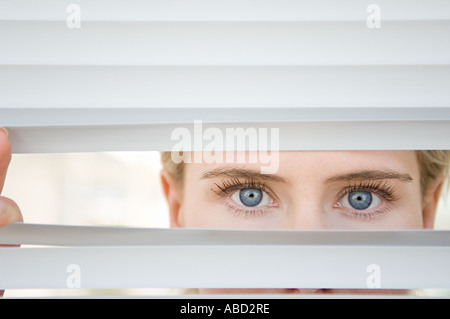 Businesswoman looking through blinds Stock Photo