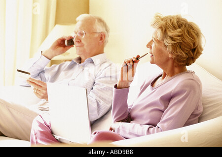 Man on cellphone and woman using laptop computer Stock Photo