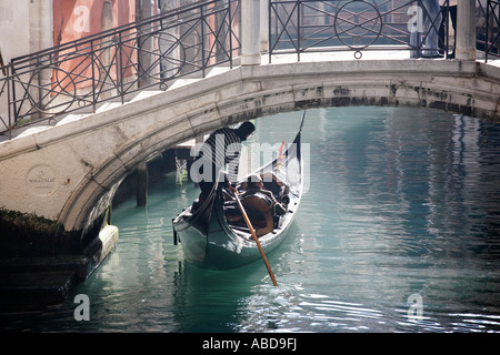 A gondolier passes beneath a bridge in Venice Italy Stock Photo