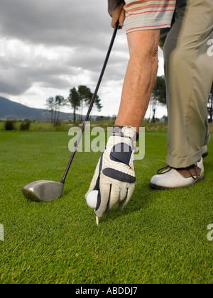 Man placing golf ball on tee Stock Photo