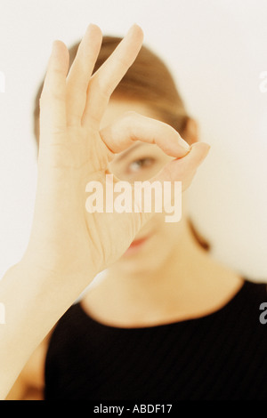 A young woman framing part of her face with hands showing her left eye Stock Photo