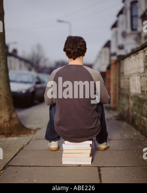 A young man sitting on a pile of books Stock Photo