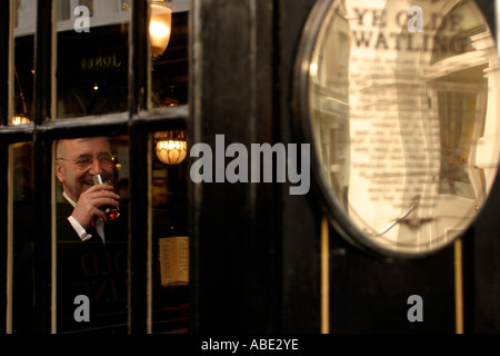 A man laughing and drinking a pint of beer in the Old Watling Pub London UK Stock Photo