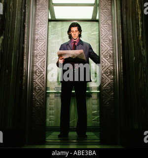 Man reading newspaper in elevator Stock Photo