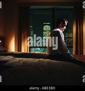 Serious looking man sitting on bed Stock Photo