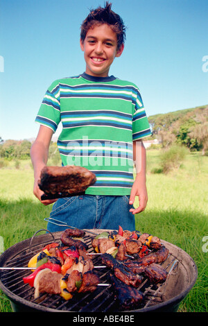 Boy cooking meat on barbeque Stock Photo